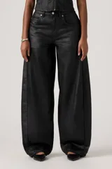 Pantalón de jean con acabado encerado negro, de corte super baggy y silueta tipo barril, con diseño de cinco bolsillos y cierre frontal con botón y cremallera.