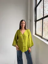 Camisa de lino color verde pistacho, de corte holgado, con escote en V y cierre frontal con botones.