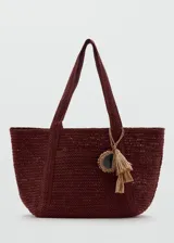 Bolso tote de tejido de fibra natural color bordó, con dos asas largas para hombro y detalle de charm colgante con flecos.