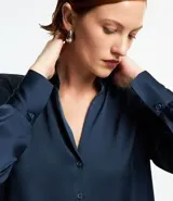 Camisa de satén color verde oliva, de manga larga con puños abotonados y cuello inglés.