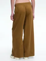 Pantalón de corte holgado y pierna ancha, confeccionado en pana color marrón. Presenta cintura elástica con cordón ajustable y diseño de tiro medio.