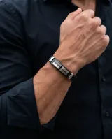 Pulsera de diseño masculino fabricada en acero inoxidable y goma negra, con detalles metálicos decorados con un patrón de guarda griega.
