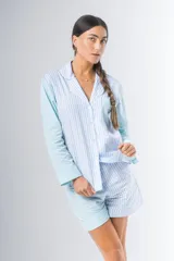 Pijama de algodón a rayas verticales celestes y blancas, compuesto por una camisa de manga larga con botones y un short con elástico en la cintura.