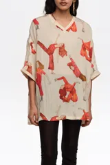 Blusa de corte oversize color beige, con estampado artístico de personas en movimiento de tonos rojos, escote en V y mangas cortas.