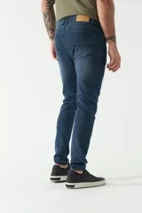 Jean skinny de hombre, color gris oscuro con efecto desgastado. Presenta cinco bolsillos, pasacinto y logo bordado.