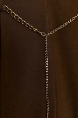 Bermuda de tiro alto color marrón oscuro, con pliegues frontales y bolsillos laterales ocultos. Incluye un cinturón metálico fino de cadena dorada que cruza la cintura.