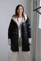 Tapado de cuero sintético negro con interior y detalles en corderito sintético color crema. Presenta capucha, cierre frontal y mangas largas con puños vueltos.