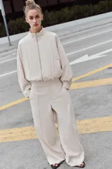 Pantalón de tiro alto con pernera recta y nervio marcado en el delantero. Cuenta con cintura elástica en la parte posterior, bolsillos delanteros y bolsillos de plastrón en la parte trasera. Cierre frontal con botón interior y ganchos.