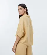 Camisa de viscosa color mostaza, de manga corta, con cuello camisero y cierre frontal con botones.