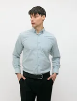 Camisa de manga larga de tejido Oxford color celeste, con cuello button-down, cierre frontal de botones y un bolsillo aplicado en el pecho.