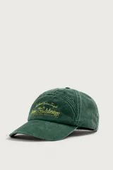 Gorra de siete paneles verde oscuro con efecto lavado, visera curva y bordado frontal en tono amarillo con la inscripción 'Bahia Montego'. Cuenta con ajuste posterior.