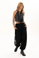 Pantalón de encaje negro con diseño floral, corte holgado y cintura elástica con cordón ajustable. Cuenta con bolsillos laterales.