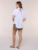 Blusa blanca de algodón texturizado con sutil relieve de rayas verticales al tono, escote en V con cuello solapa pequeño y mangas cortas.