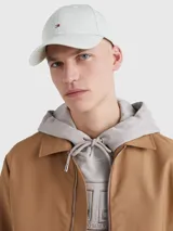 Gorra de béisbol color gris claro, confeccionada en algodón. Presenta ojales de ventilación, botón en la parte superior y hebilla metálica ajustable en la parte trasera con logo grabado de Tommy Hilfiger. El logo de la marca está bordado en el frente.