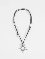 Collar de cordón negro con dije metálico plateado en forma de sol con diseño irregular y estilo gótico.