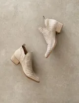 Botín corto color beige con textura símil piel de cocodrilo, taco de madera y laterales con corte en V.