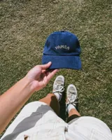 Gorro de pana color mostaza con visera y bordado frontal con la palabra "Yamba".