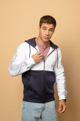 Campera con capucha y cierre frontal, con diseño en bloques de color blanco, azul marino y gris, mangas largas con puños elastizados y bolsillos tipo canguro.
