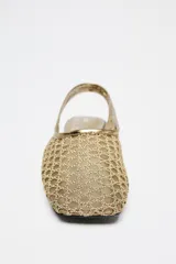 Zapato plano destalonado tipo bailarina color dorado, con efecto metalizado y detalle trenzado en el corte. Estilo mule con tira trasera con pieza elástica. Suela de 1,5 cm de altura.