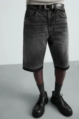Bermuda de denim de algodón, color negro lavado, de corte ancho (baggy fit) y tiro medio. Presenta cinco bolsillos y bajo con acabado irregular deshilachado.