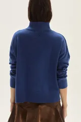 Polera de tejido de punto color azul, con cuello alto, manga larga y puños acanalados.