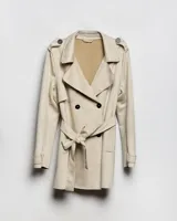 Campera trench de gabardina en color beige, con solapa cruzada, doble botonadura frontal, hombreras y cinturón ajustable para anudar en la cintura. Presenta bolsillos delanteros y puños ajustables con tiras.