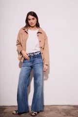 Sobrecamisa negra de estilo shacket, confeccionada en tejido de gamuza sintética. Presenta cuello camisero, cierre frontal de botones y dos bolsillos de parche con solapa en el pecho. El calce es oversize y las mangas son largas.