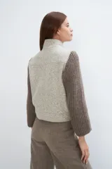 Campera de lana fina color crema, con cuerpo estructurado y mangas de tejido de punto acanalado. Presenta cuello alto, cierre frontal con botones y bolsillos laterales con doble abertura.