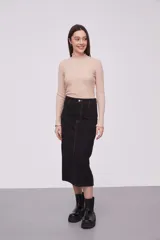 Falda midi de jean color negro, de tiro alto y corte recto. Presenta costuras a la vista en color ocre y cierre frontal con botón y cremallera.