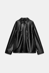 Camisa de efecto piel en color negro, con cuello solapa, manga larga y bolsillos de plastrón en el delantero. Presenta cierre frontal con botones ocultos por tapeta.