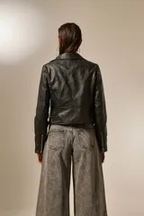 Campera de cuero sintético negra, con cuello solapa, cierre asimétrico con cremallera, bolsillos laterales con cremallera y corte entallado.