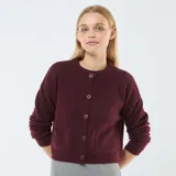 Cárdigan color borgoña de tejido de punto, corte cropped, con cuello redondo, cierre frontal con botones y bolsillos de parche.