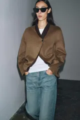 Blazer oversize de Zara Woman Collection confeccionado en mezcla de lana, con cuello sin solapa, manga larga y cierre frontal con botón. Presenta bolsillos delanteros con solapa.