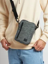 Bandolera gris con textura, de forma rectangular y correa larga regulable negra.