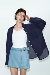Falda pantalón cruzada de denim en color celeste, con diseño cruzado al frente, cierre frontal oculto y hebilla decorativa redonda en la cintura.