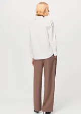 Camisa de popelín color blanco, de manga larga, con cierre frontal de botones y cuello camisero con solapa.
