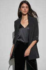 Blazer negro de corte recto con solapa clásica y mangas tres cuartos con detalles de trabilla y botón metálico.