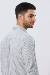 Camisa de lino rayada de manga larga, con cuello camisero, cierre frontal de botones y bordado sutil en el pecho.