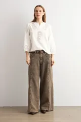 Blusa blanca de corte holgado con cuello mao y escote en V. Presenta detalles de bordado calado en el pecho y en los puños de las mangas tres cuartos.