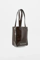 Bolso tipo tote de charol color marrón, con diseño vertical, doble asa de hombro y logo de la marca estampado en la parte inferior. Cuenta con terminaciones en contraste y estructura rígida.