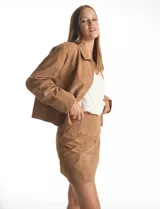 Chaqueta de efecto gamuza color marrón, con cuello solapa, cierre frontal con botones y bolsillos delanteros. Presenta costuras desplazadas en los hombros y forro interno a tono.