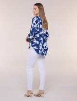 Blusa de gasa de calce suelto y caída ligera, color azul con estampado floral blanco. Presenta escote en V con cuello mao, tabla central, mangas largas regulables con presilla y botón, ruedo redondeado de estilo mullet y espalda con canesú y pliegue central.