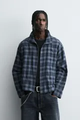 Camisa boxy fit de cuadros en tonos azules y negros, confeccionada en tejido con mezcla de algodón. Cuenta con cuello solapa, manga larga y cierre frontal con cremallera.