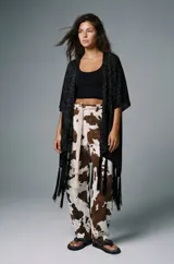 Pantalón ancho de tiro alto con estampado de vaca en tonos marrón y blanco. Se ajusta a la cintura con un cinturón de cuerda trenzada de color crudo.