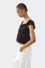 Blusa marrón de punto pointelle con textura, escote corazón, detalle cut-out con cordón de ajuste en el busto, mangas cortas circulares con volados y diseño acampanado.
