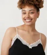 Conjunto de pijama negro, compuesto por un top de tirantes con encaje blanco en el escote y un short con encaje blanco en el ruedo.