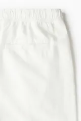 Short de corte relajado confeccionado en tejido liviano de algodón y viscosa, color blanco. Presenta cintura elástica con cordón de ajuste, bolsillos laterales al bies y un bolsillo insertado en la parte posterior.