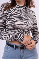 Polera de cuello alto y manga larga con estampado animal print de leopardo, confeccionada en tejido elástico ajustado al cuerpo.