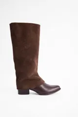 Bota de caña alta confeccionada en una combinación de cuero vacuno liso en la parte inferior y gamuza en la caña. Presenta un diseño de estilo ecuestre con taco bajo cuadrado y cierre interno.