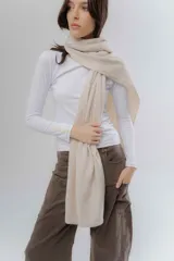 Bufanda de tejido suave en color beige, con diseño liso y terminaciones clásicas.